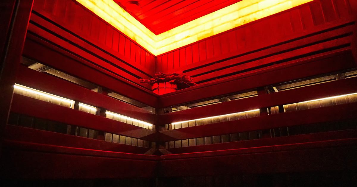 Modern wooden sauna with two long benches in different levels with a long strip of red lights in the ceiling.